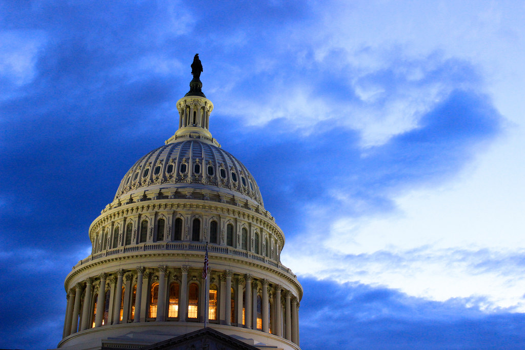 Capital Building dome in Washington, DC, lit up at dusk with a dark blue cloudy sky